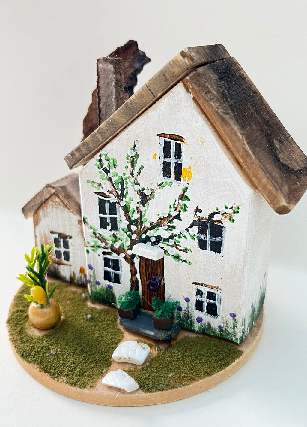 Miniature diorama with a house, and plants on a white background (RRH1043)