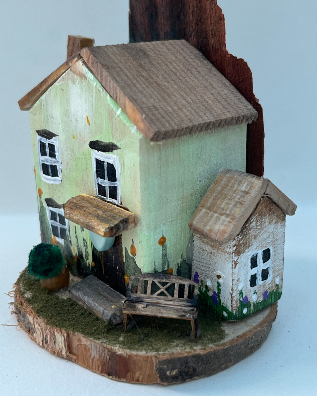 Miniature diorama with a house, bench, and plants on a white background (RRH1039)