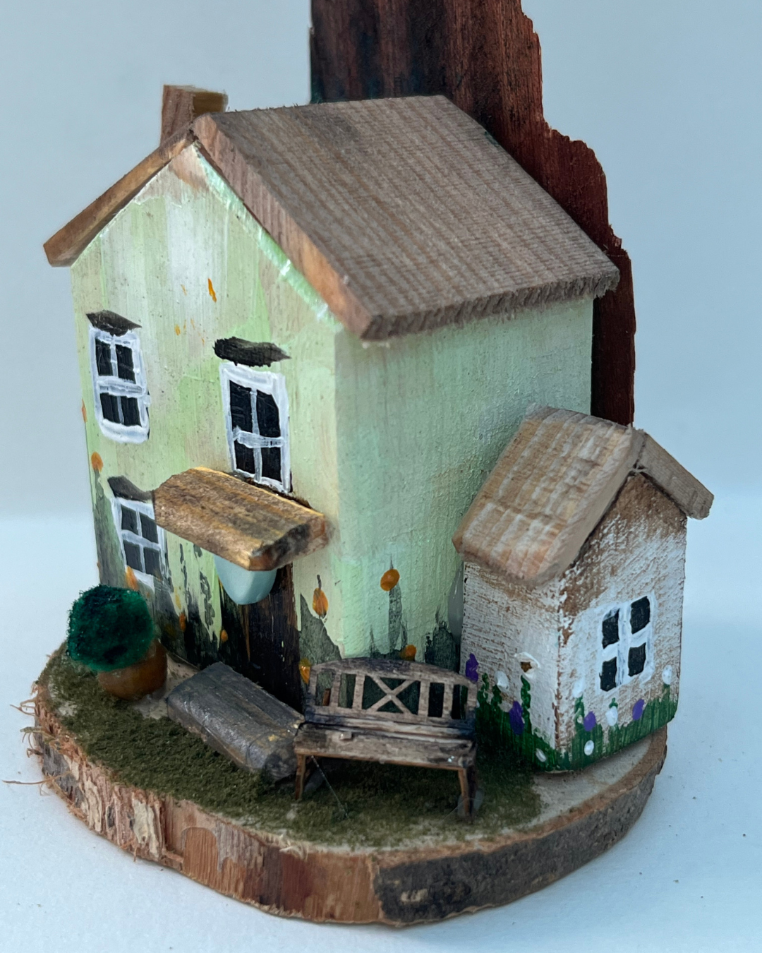 Miniature diorama with a house, bench, and plants on a white background (RRH1039)