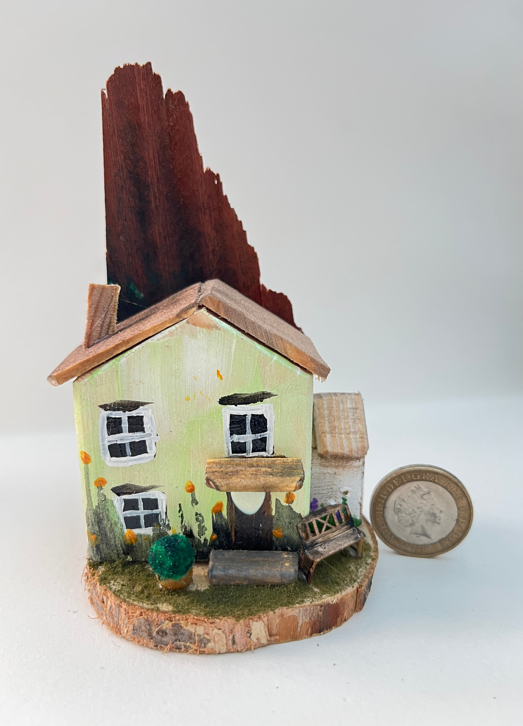 Miniature diorama with a house, bench, and plants on a white background (RRH1039)